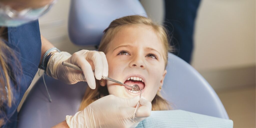Dentists with a patient during a dental intervention to girl.